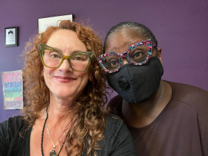 two people smiling, one wears a mask