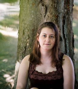Megan Alpert Photo of a white woman in a dark shirt in front of a tree