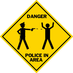 Yellow Caution sign warning of Danger Police in Area, image of Cop shooting citizen