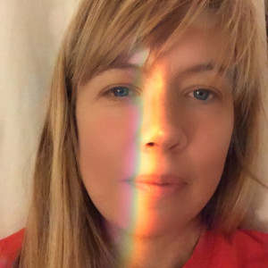 Emily Kendal Frey Photo of a blond woman in a red shirt with a beam of sunlight on her face