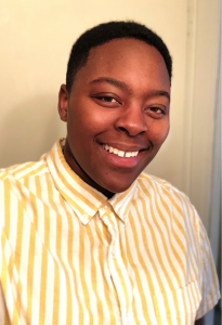 Smiling African American woman with short hair, wearing a yellow and white striped shirt.