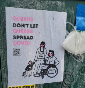 wheatpasted poster with headline "Queers don't let queers spread Covid"; drawing of three people, two adults, one in a wheelchair, all wearing pink respirator masks.  The standing adult wears a t-shirt that says "We Keep Us Safe"