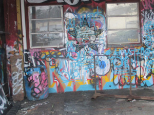 A graffiti-covered corner of some shack, with the Self Help Radio logo on the wall too.