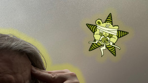 A telepath, fingers to his temple, communes with the Self Help Radio logo.