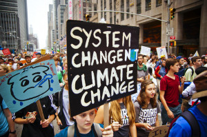 photo of protest marchers with sign system change not climate change